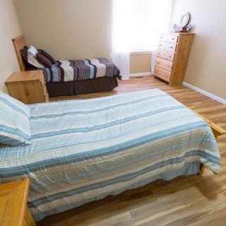A tidy bedroom with two beds, a dresser, and wooden flooring.