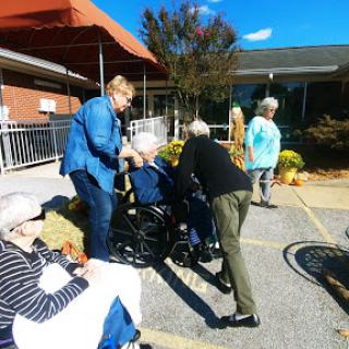 Caregivers assisting elderly individuals during a community event in a sunny outdoor setting.