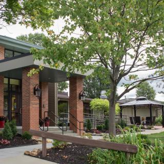 A modern building with a brick facade surrounded by trees and landscaped greenery.