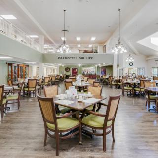 A spacious and well-lit dining room with neatly arranged tables and chairs.