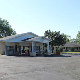 A view of a residential building surrounded by trees and a spacious parking lot.