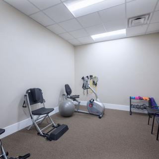 A small exercise room with gym equipment including a stationary bike and resistance bands.