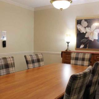A cozy dining room with a wooden table, plaid chairs, and flower-themed artwork on the wall.