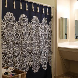 A bathroom with a patterned shower curtain and a sink with a mirror.