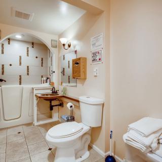 An accessible bathroom featuring a walk-in shower, toilet, and sink with towels neatly folded nearby.