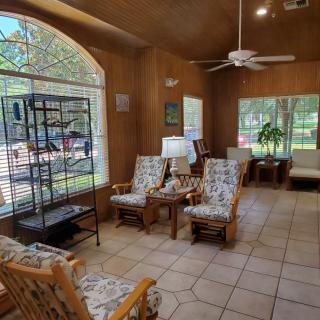 A cozy living room with wicker furniture, large windows, and abundant natural light.