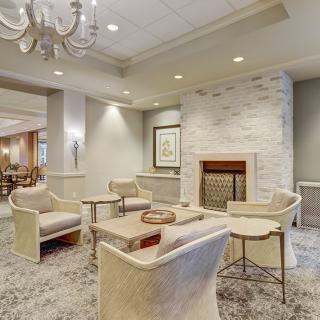 A modern living room with a cozy seating area, featuring a fireplace and elegant chandelier.
