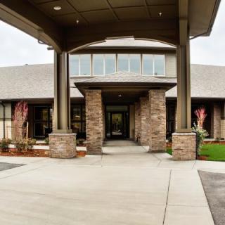 A modern building with a brick facade and a covered entrance supported by columns.