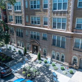 A view of a stylish apartment building with landscaped surroundings and parked cars.