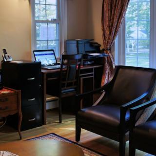 A cozy home office with a desk, computer, and comfortable seating by the window.