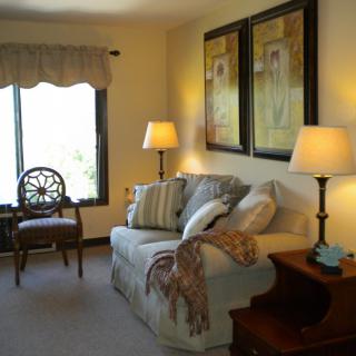 A cozy living room with a sofa, decorative pillows, and lamps beside framed artwork.