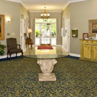 A well-decorated lobby area featuring a central glass table, a chandelier, and traditional furnishings.