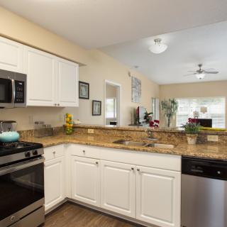 A modern kitchen with white cabinets, stainless steel appliances, and granite countertops.