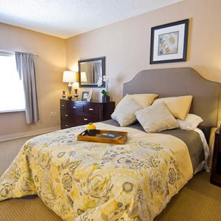 A cozy bedroom with a stylish bed, adorned with cushions and a patterned comforter, flanked by bedside tables and lamps.