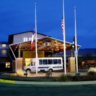 A hotel entrance at night featuring a shuttle van and flags displayed in front.