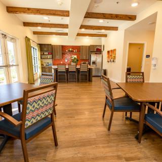 A modern kitchen and dining area featuring wooden floors, tables, and chairs.