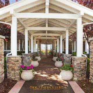 A beautifully designed entrance with a pathway lined by columns and potted plants.