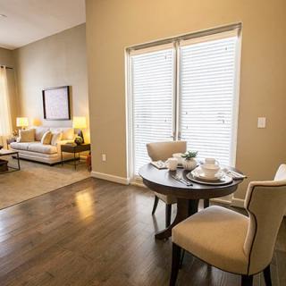 A cozy living room and dining area featuring wood flooring, comfortable seating, and ample natural light.