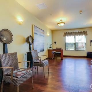 A spacious salon interior with chairs and hair dryers, featuring wood flooring and ample natural light.