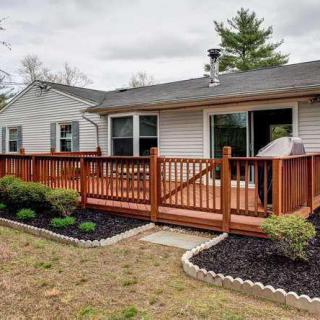 A cozy backyard featuring a wooden deck with a fence, surrounded by neatly landscaped garden beds.