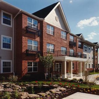A modern residential building featuring multiple balconies and landscaped surroundings.