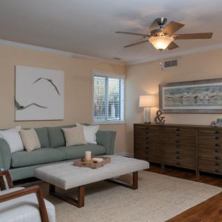 A cozy living room with modern decor, featuring a green sofa, wooden furniture, and abstract artwork.