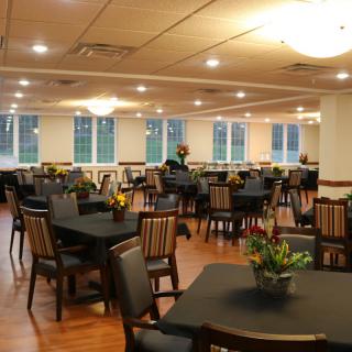 An inviting dining area with neatly arranged tables and chairs, complemented by soft lighting and decorative plants.