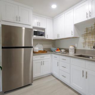 A modern kitchen with white cabinets and stainless steel appliances in a compact layout.