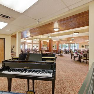A spacious interior with a piano and dining area featuring tables and chairs.