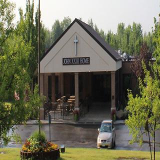 A church building with a car parked outside, surrounded by trees.