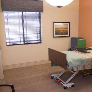 A well-lit hospital room featuring a patient bed and natural light from the window.