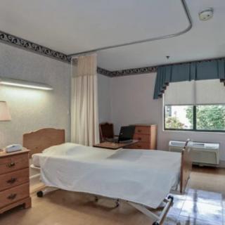 A hospital room with a single bed and simple furnishings.