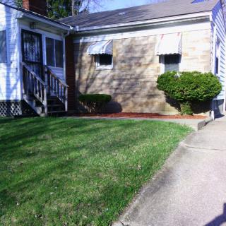 A small residential house with a neatly maintained lawn and pathway.