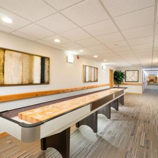 A modern hallway features a shuffleboard table and contemporary artwork on the walls.