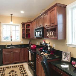 A cozy kitchen with wooden cabinets and a black countertop featuring various kitchen accessories.