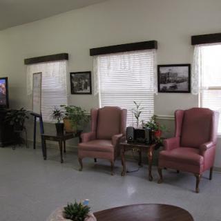 A cozy waiting area featuring pink armchairs, greenery, and framed photographs on the walls.