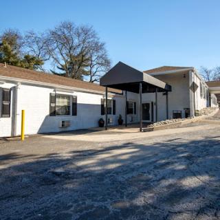A view of a modern residential building with a covered entrance and a sloped driveway.