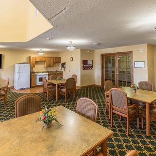 A cozy dining area with several tables and a small kitchen equipped with appliances.