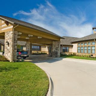 A modern residential building with a spacious driveway and green surroundings.