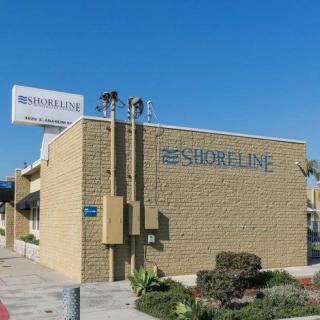 Exterior view of the Shoreline Motel with a visible sign and surrounding landscape.