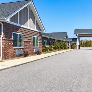 A modern building with a driveway and landscaped surroundings.