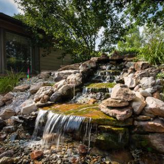 A serene waterfall cascading over rocks in a beautifully landscaped garden.