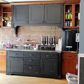 A modern kitchen with dark cabinets and a brick backsplash.