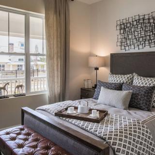 A stylish bedroom with a neatly made bed, decorative pillows, and a tray on top.