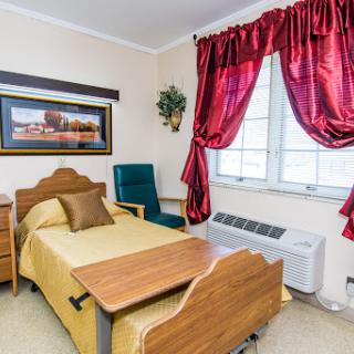 A cozy bedroom setup featuring a bed, armchair, and decorative curtains.