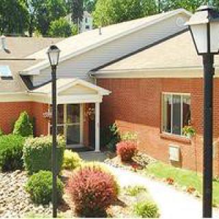 A brick building with a landscaped garden and lampposts at the entrance.