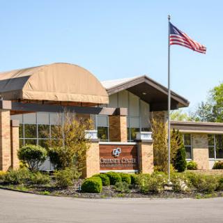 A modern commercial building with an American flag on display, surrounded by well-maintained landscaping.