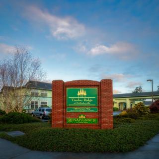 A brick sign in front of a school building on a cloudy day.