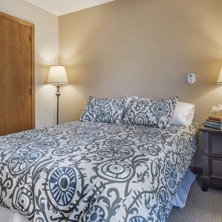 A cozy bedroom featuring a patterned comforter and stylish lighting.