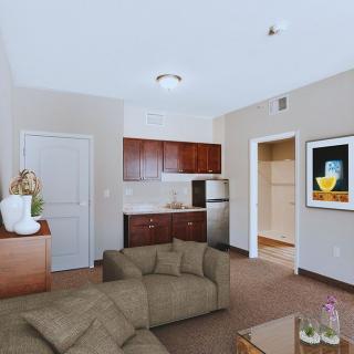 A modern living room with a kitchenette, featuring a comfortable sofa and stylish artwork.